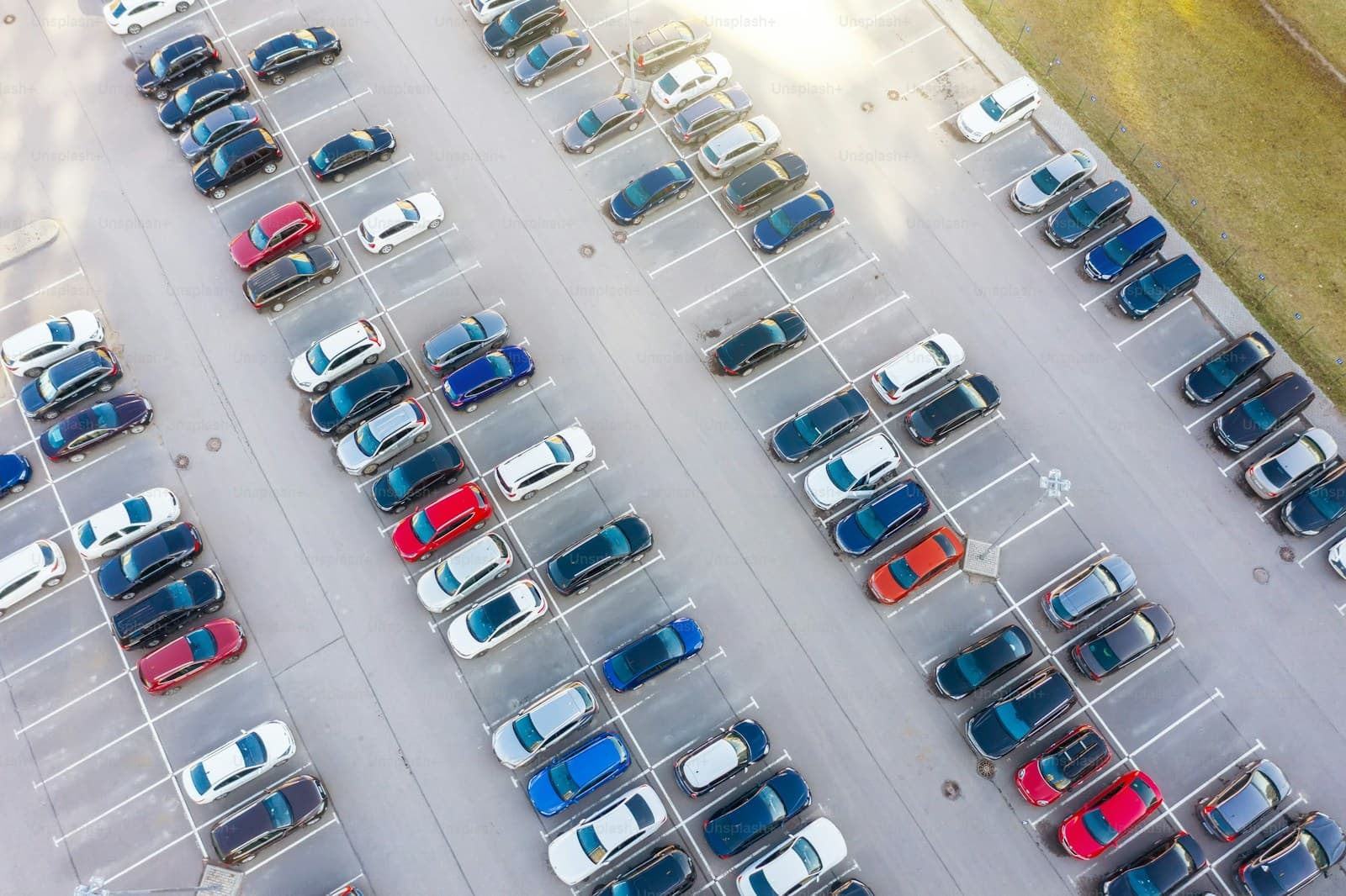 Aerial view of a parking lot with many cars arranged in rows, shot from above showing organized parking spaces