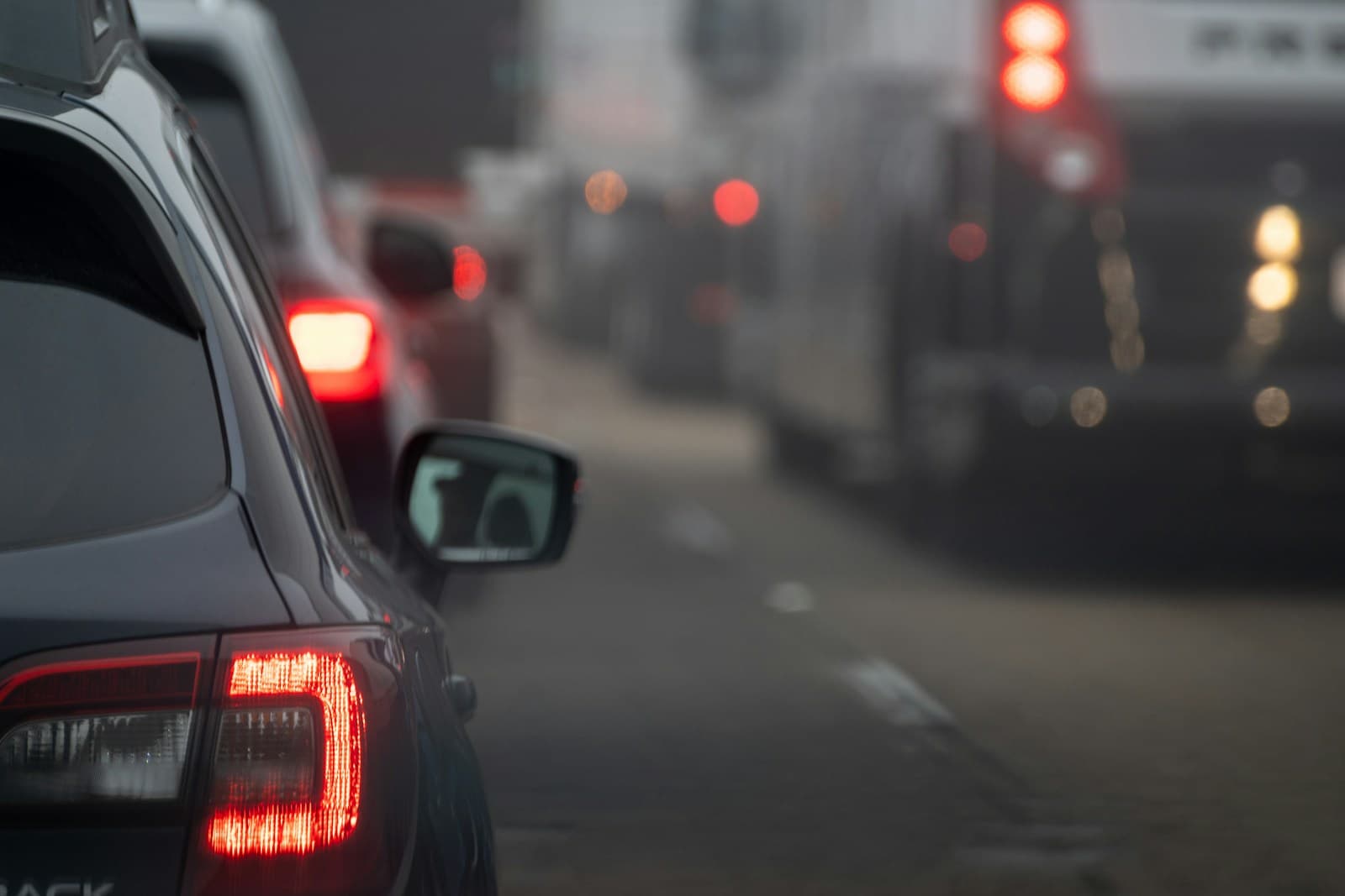 Cars in heavy traffic at night with red brake lights glowing, creating a moody urban street scene